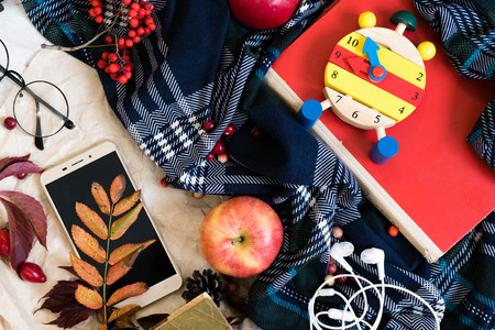 heart clock with glasses and mobile phone on red book ,education concept, mobile phone with headphones, autumn leaf on a vintage table surface, selective focusの写真素材