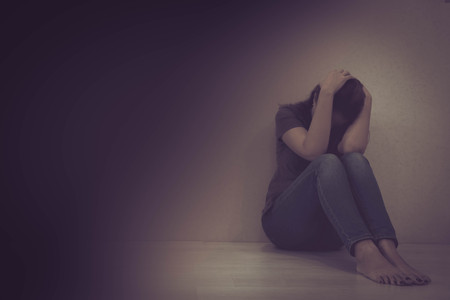 Depressed teenager sitting holding head in hands, stressed sad young woman having mental problems, feeling bad, need psychological help, addicted heartbroken girl experiencing adolescence crisisの写真素材