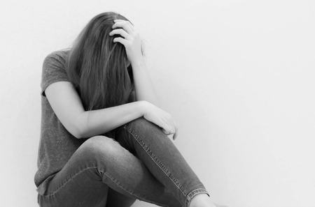 Depressed teenager sitting holding head in hands, stressed sad young woman having mental problems, feeling bad, need psychological help, addicted heartbroken girl experiencing adolescence crisisの写真素材