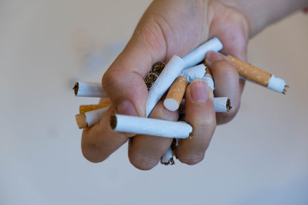 Stop smoking. Close up of male hand breaking cigarettes with his fist. Isolated and copy space in left sideの写真素材