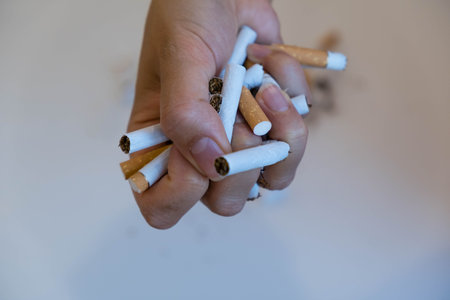 Stop smoking. Close up of male hand breaking cigarettes with his fist. Isolated and copy space in...