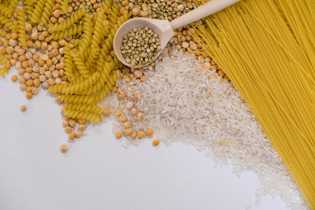Set of products with complex carbohydrates on white background. wooden spoon, a range of cereals, pasta. Gluten free flour and cereals millet, green buckwheat, basmati rice,up viewの写真素材