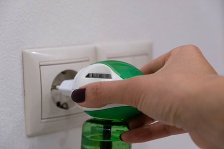 Electric mosquito trap device. insect killer. A woman puts a raptor from an insect into an electrical outlet.の写真素材