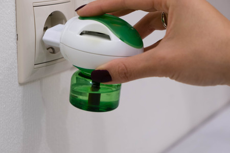 Electric mosquito trap device. insect killer. A woman puts a raptor from an insect into an electrical outlet.の写真素材