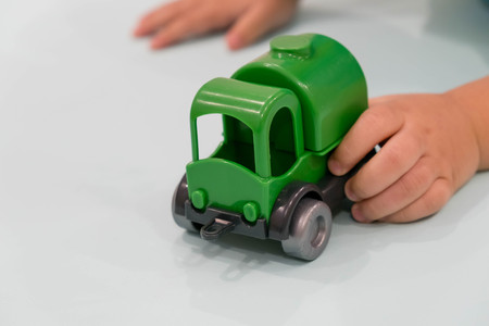 Child hands playing with miniature toy cars, wooden background, top viewの写真素材