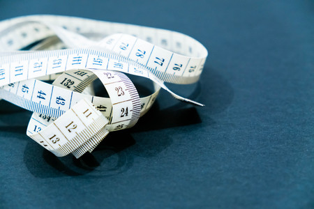 Close up tailor measuring tape on a black background. White measuring tape shallow dept of field.の写真素材