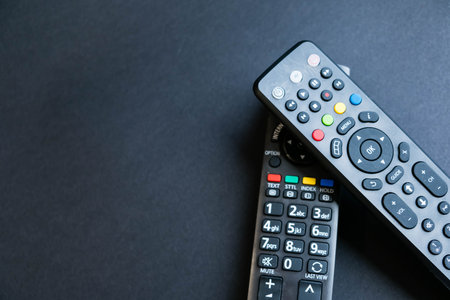 Remote controllers on a table. Top view, flat lay. Close up on a black background. copy space for text, selective focus. smart tvの写真素材