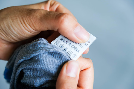 Woman checking the care label. selective focus. Woman's hands holding clothes label with cleaning instructions. lose-up Of Person Reading The Clothing Label Showing Washing Instructions.の写真素材