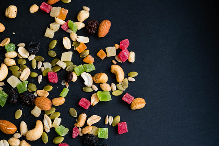 Composition with dried fruits and assorted nuts. Delicacies. Various nuts on stone table. Different kinds of nuts. Close up on a black background. Top view, flat lay. copy space for textの写真素材
