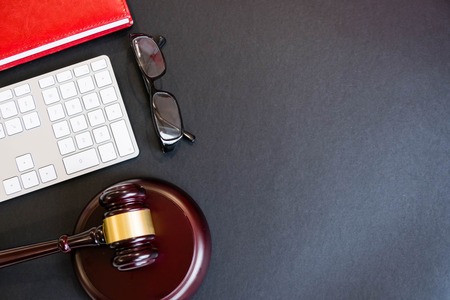 Top view, flat lay. Close up on a black background. copy space for text, selective focus. justice and law concept.Lawyer workplace with laptop and documents with dark woodenの写真素材