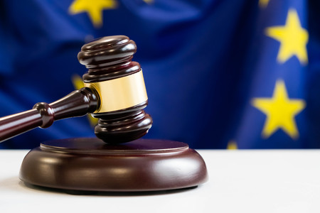 Judges wooden gavel with EU flag in the background. Symbol for jurisdiction. Wooden gavel on european union flagの写真素材