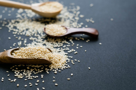 Organic natural sesame seeds wooden spoon. toasted sesame seeds. Raw, whole, unprocessed. Natural light. Selective focus. Close up on a black background. Top view, flat lay. copy space for text.の写真素材