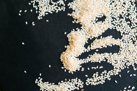 Organic natural sesame seeds wooden spoon. toasted sesame seeds. Raw, whole, unprocessed. Natural light. Selective focus. Close up on a black background. Top view, flat lay. copy space for text.の写真素材