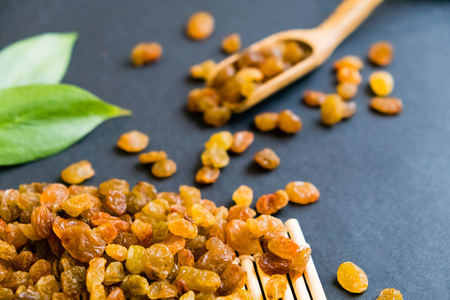 Raisins on a wooden spoon. Natural light. Selective focus. Close up on a black background. Top view, flat lay. copy spaceの写真素材