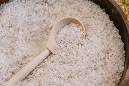 Raw white rice in wooden bowl and spoon on burlap, food ingredient photoの写真素材
