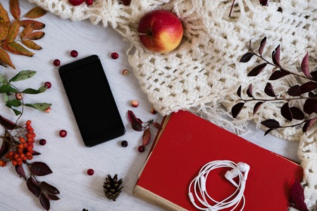 Cozy home with cup of coffee and a book. Hygge style. Mug of black coffee wrapped in warm scarf on wooden board. Top view, vintage style, Still life.の写真素材