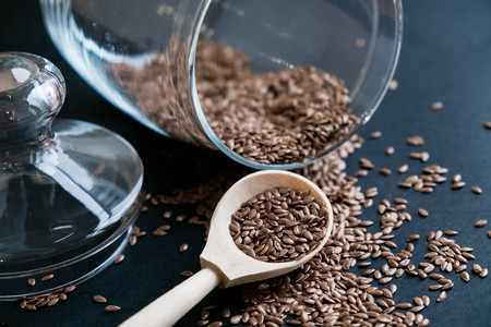 Flax seeds in spoons over dark background. Natural light. Selective focus. Close up on a black background. Top view, flat lay. copy space.の写真素材