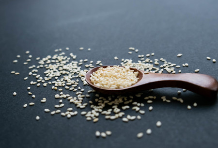 Organic natural sesame seeds wooden spoon. toasted sesame seeds. Raw, whole, unprocessed. Natural light. Selective focus. Close up on a black background. Top view, flat lay. copy space for text.の写真素材