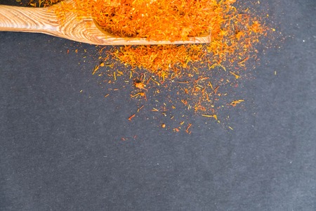 Dried saffron spice on black background. Raw Organic pistil powder saffron are scattered on the table. Red Saffron Spice in a wooden spoon on black backgroundの写真素材