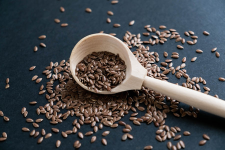 Flax seeds in spoons over dark background. Natural light. Selective focus. Close up on a black background. Top view, flat lay. copy space.の写真素材