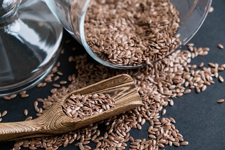 Flax seeds in spoons over dark background. Natural light. Selective focus. Close up on a black background. Top view, flat lay. copy space.の写真素材