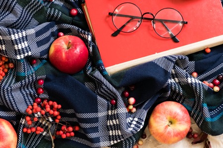 Cozy home with cup of coffee and a book. Hygge style. Mug of black coffee wrapped in warm scarf on wooden board. Top view, vintage style, Still life.の写真素材