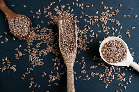 Flax seeds in spoons over dark background. Natural light. Selective focus. Close up on a black background. Top view, flat lay. copy space.の写真素材