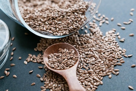 Flax seeds in spoons over dark background. Natural light. Selective focus. Close up on a black background. Top view, flat lay. copy space.の写真素材
