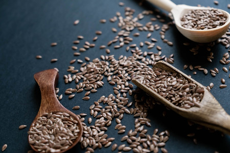 Flax seeds in spoons over dark background. Natural light. Selective focus. Close up on a black background. Top view, flat lay. copy space.の写真素材