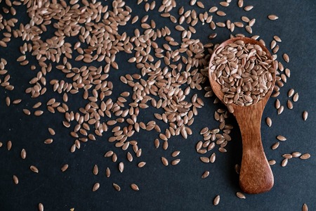 Flax seeds in spoons over dark background. Natural light. Selective focus. Close up on a black background. Top view, flat lay. copy space.の写真素材