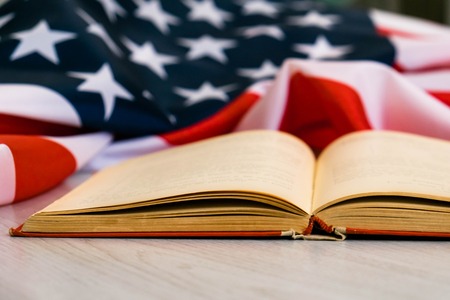 Opened book and USA flag. US flag behind a book. Education is power. You should know your rights.の写真素材