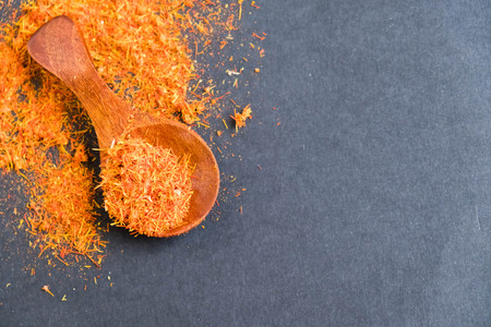 Dried saffron spice on black background. Raw Organic pistil powder saffron are scattered on the table. Red Saffron Spice in a wooden spoon on black backgroundの写真素材