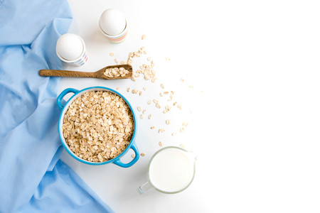 Oat flakes plate with milk, orange, eggs on a wooden white table. Top view of healthy oat flakes breakfast. Copy space. blue napkin Breakfast in bed plate, breakfast table buffet. Healthy ingredientsの写真素材
