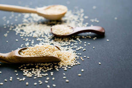 Organic natural sesame seeds wooden spoon. toasted sesame seeds. Raw, whole, unprocessed. Natural light. Selective focus. Close up on a black background. Top view, flat lay. copy space for text.の写真素材