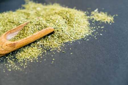 Dried oregano herbs in wooden spoon. Natural light. Selective focus. Close up on a black background. Top view, flat lay. copy space.の写真素材