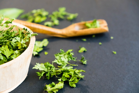 Dried cilantro leaves on a wooden spoon. Natural light. Selective focus. Close up on a black background. Top view, flat lay. copy space. dried grapes.の写真素材