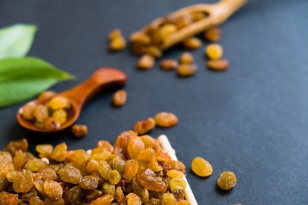 Raisins on a wooden spoon. Natural light. Selective focus. Close up on a black background. Top view, flat lay. copy spaceの写真素材