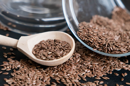 Flax seeds in spoons over dark background. Natural light. Selective focus. Close up on a black background. Top view, flat lay. copy space.の写真素材