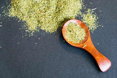 Dried oregano herbs in wooden spoon. Natural light. Selective focus. Close up on a black background. Top view, flat lay. copy space.の写真素材