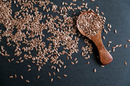 Flax seeds in spoons over dark background. Natural light. Selective focus. Close up on a black background. Top view, flat lay. copy space.の写真素材