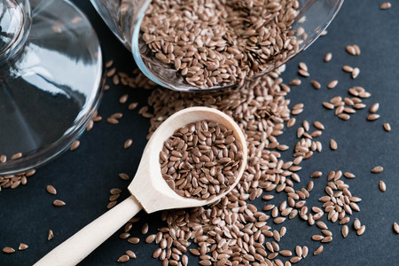 Flax seeds in spoons over dark background. Natural light. Selective focus. Close up on a black background. Top view, flat lay. copy space.の写真素材