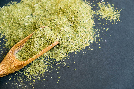 Dried oregano herbs in wooden spoon. Natural light. Selective focus. Close up on a black background. Top view, flat lay. copy space.の写真素材