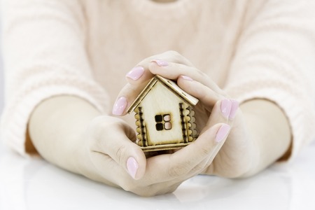 Female hands saving small house with a roofの写真素材