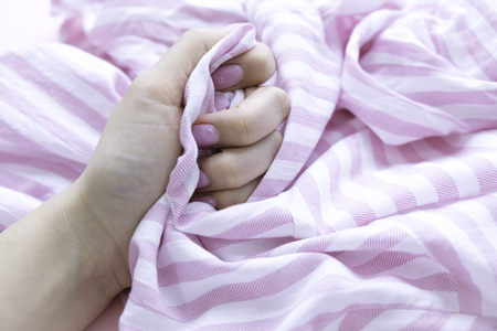 Hand sign orgasm of woman on white bed , Hand of female pulling white sheets in ecstasy , feeling and emotion conceptの写真素材