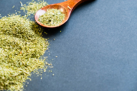 Dried oregano herbs in wooden spoon. Natural light. Selective focus. Close up on a black background. Top view, flat lay. copy space.の写真素材
