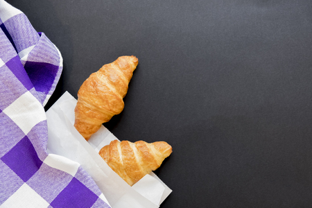 Tasty croissants in white paper bag. Rustic wooden background with sweet dessert. Top view.の写真素材