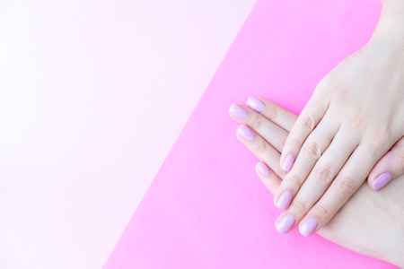 Stylish trendy female manicure. Beautiful young woman's hands on pink and blue background.の写真素材