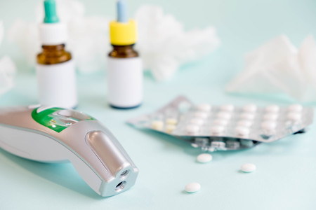 Spray for the nose or a pill to treat colds and gripes. Glass Bottle with medicines and paper handkerchiefs on a green background. Copy space for textの写真素材