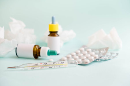 Spray for the nose or a pill to treat colds and gripes. Glass Bottle with medicines and paper handkerchiefs on a green background. Copy space for textの写真素材