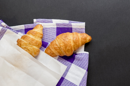 Tasty croissants in white paper bag. Rustic wooden background with sweet dessert. Top view.の写真素材